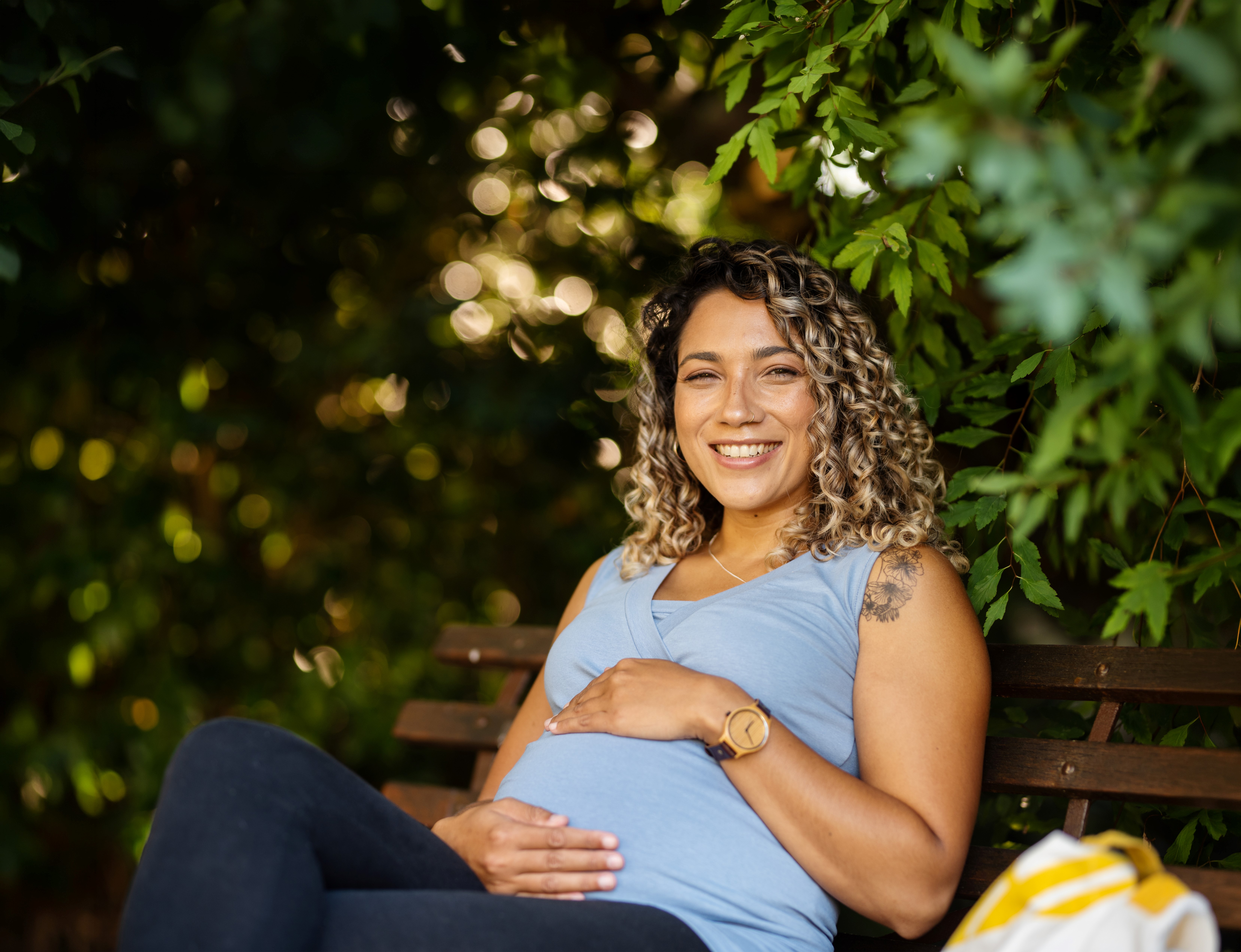 A pregnant woman sitting on a bench outdoors